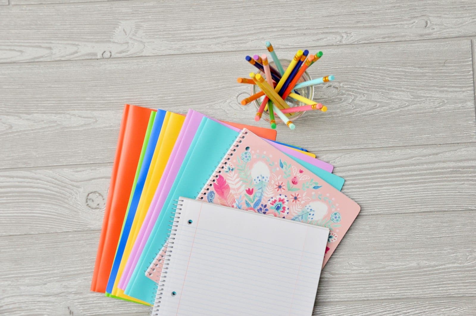 Colorful school notebooks with a jar of pencils